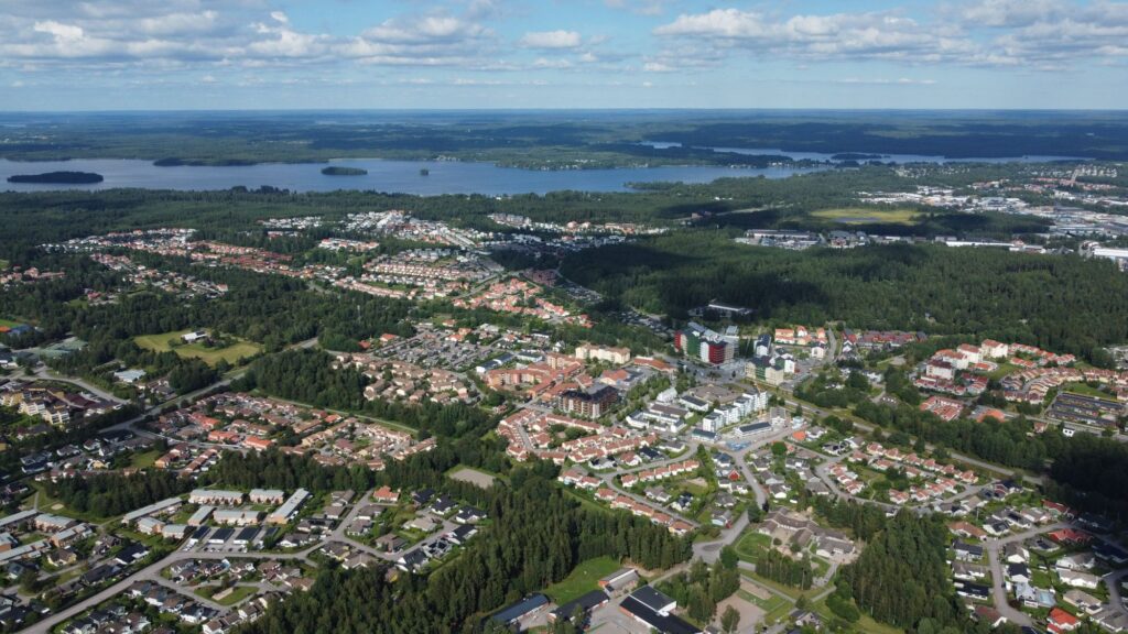 Bostadsområden, skog och sjöar i en svensk kommun, sett från ovan