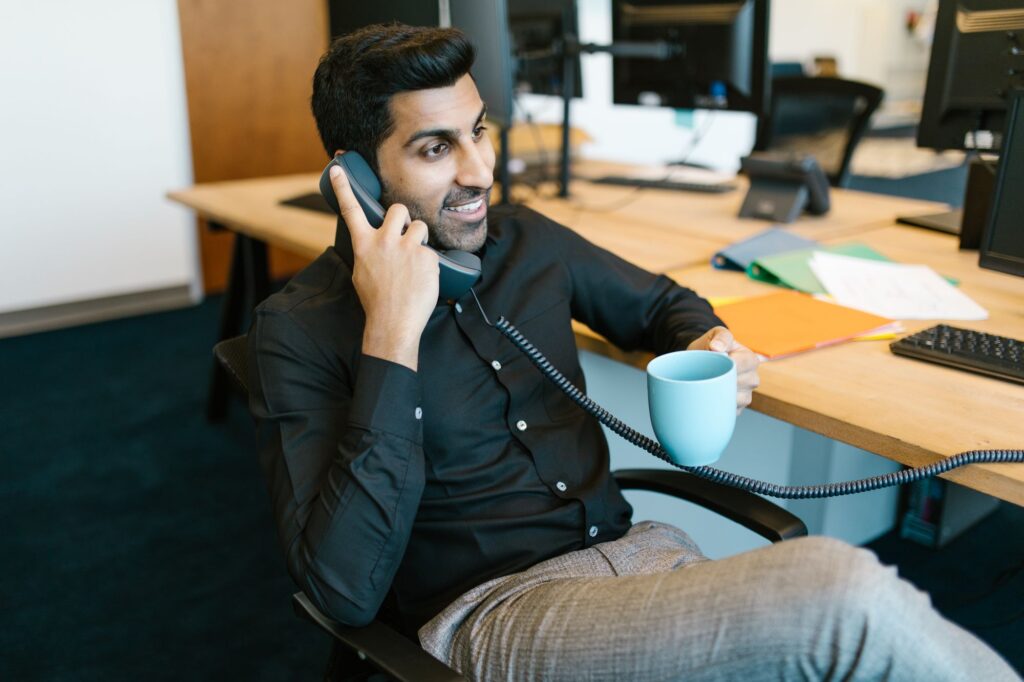 Man som talar i telefon vid sitt skrivbord på kontoret