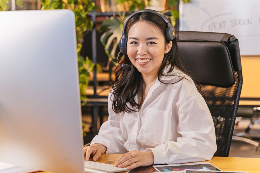Leende telefonist med headset vid sin dator